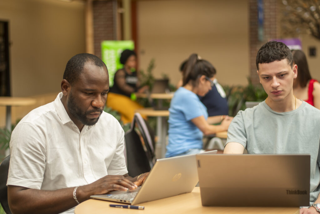 Students working on laptops in the Nashua Community College atrium