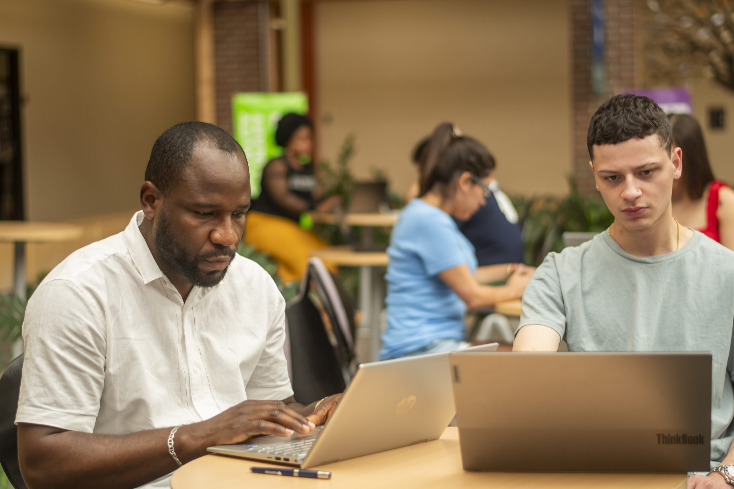 Students working on laptops in the Nashua Community College atrium